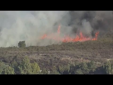 Firefighters try to put out brush fire in Poway during Red Flag Warning