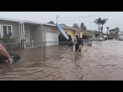 San Diego flood | Woman walks through flood waters to find car