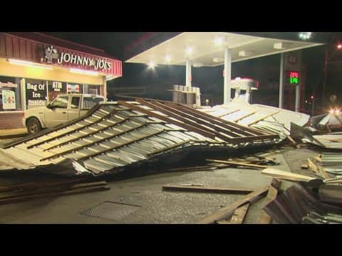 Strong winds blows a roof onto power lines near a gas station
