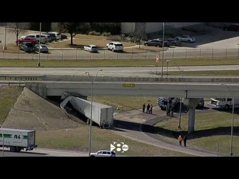 Semi crashes and becomes lodged under a bridge
