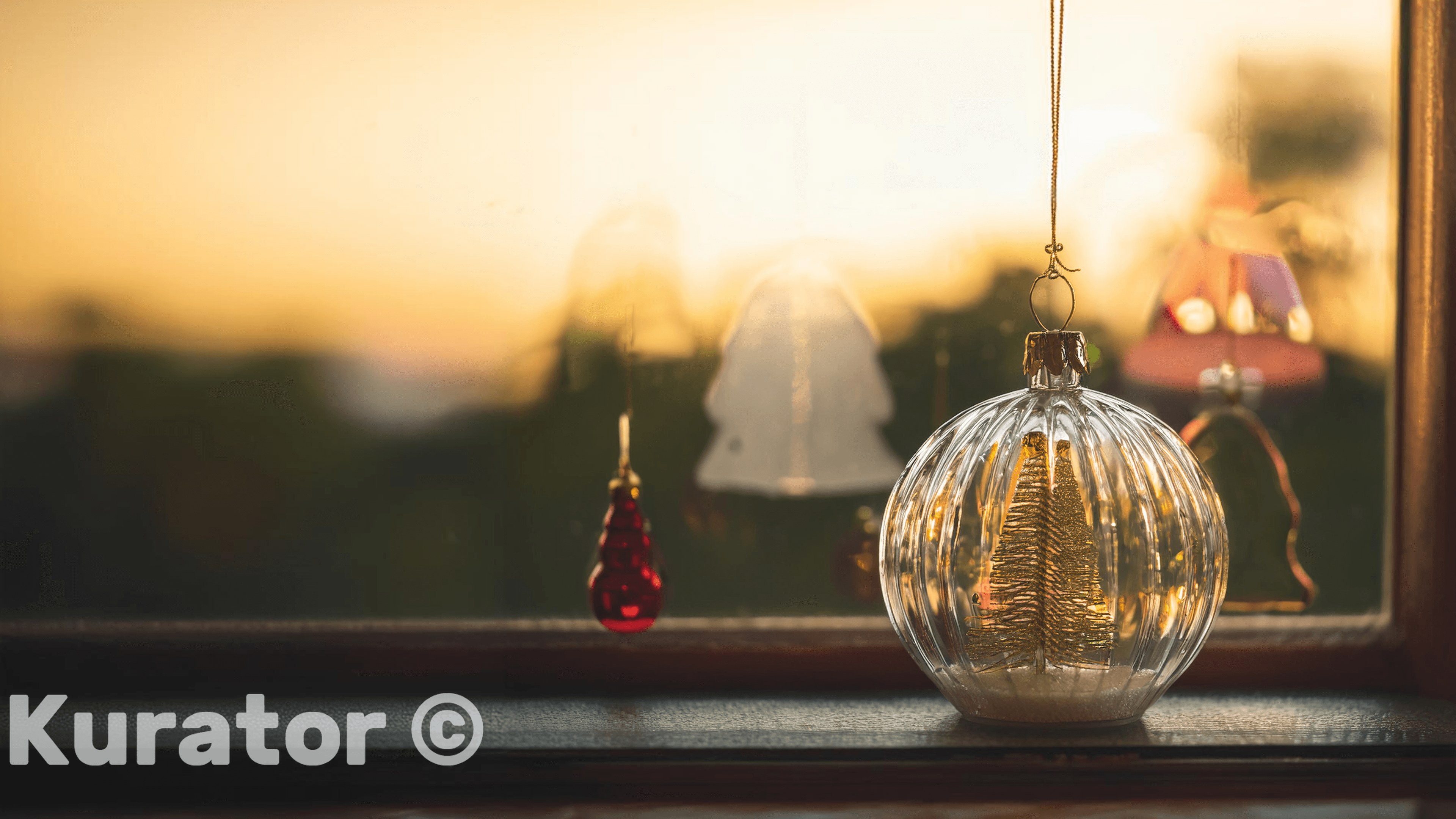 Christmas ornament with a tiny golden tree inside, hanging near a window at sunset. A warm and cozy holiday scene, blending festive decor with a serene evening atmosphere